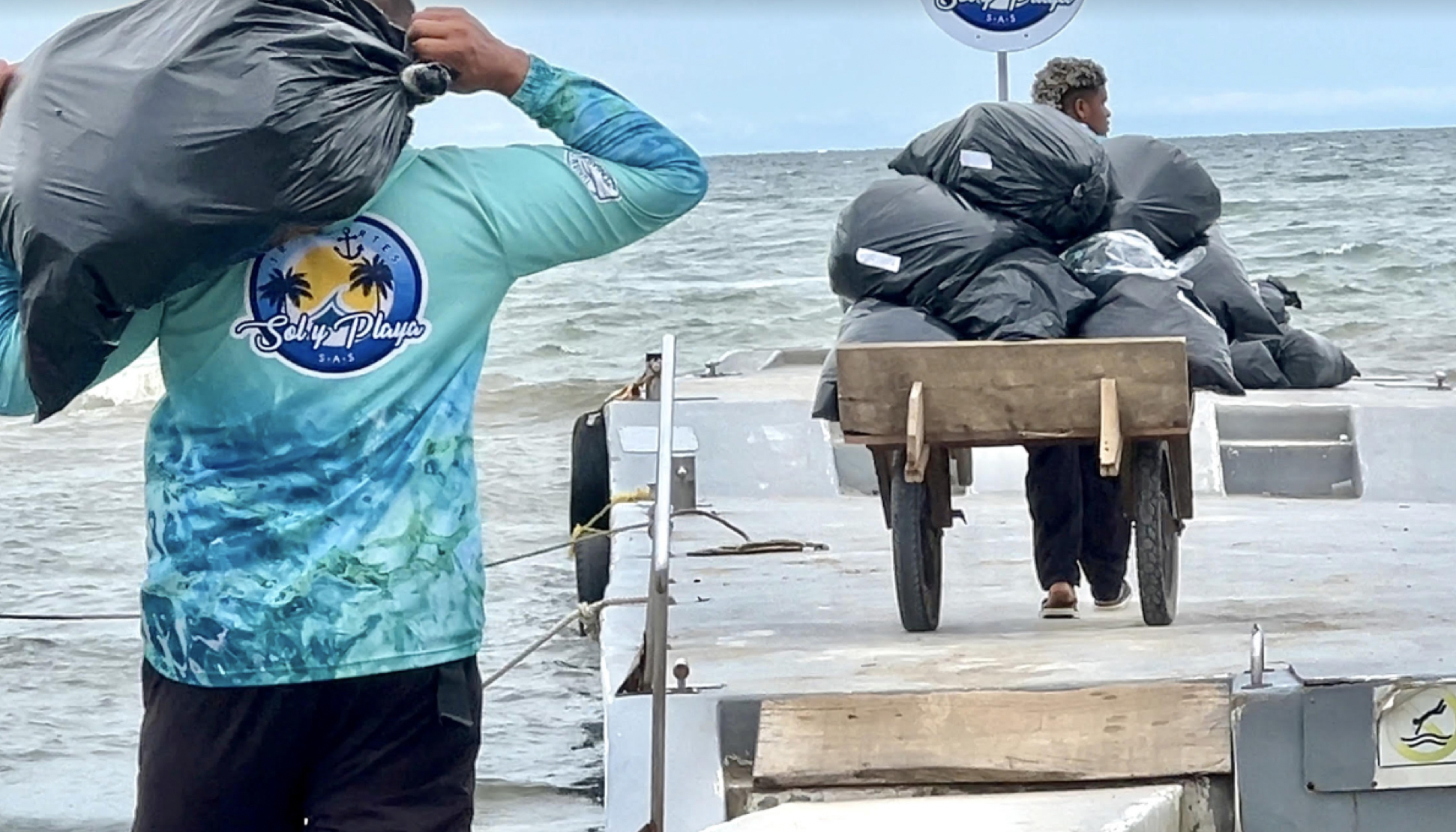 Workers prepare to load the black dry bags containing immigrant camping gear in Necocle, Colombia, for the boat ride over to Capurgana